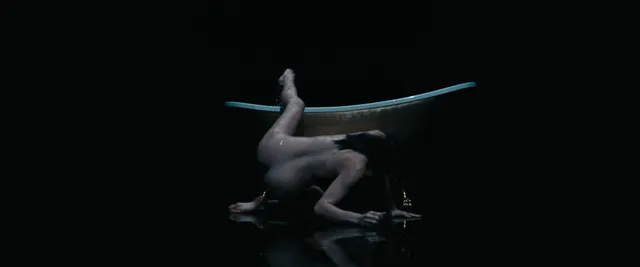 Anne Hathaway posing in a dark stage scene.