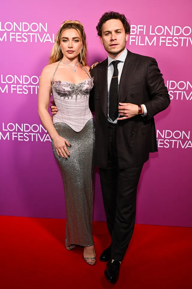 Florence Pugh posing beside a man in a silver gown at a film festival.