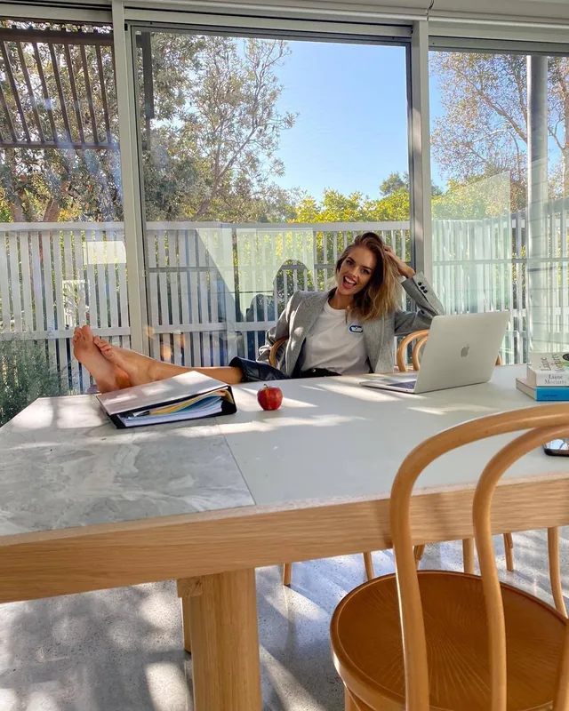 Samara Weaving resting bare feet on a table beside a laptop.