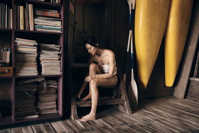 Phoebe Tonkin sitting beside shelves during a portrait shoot.
