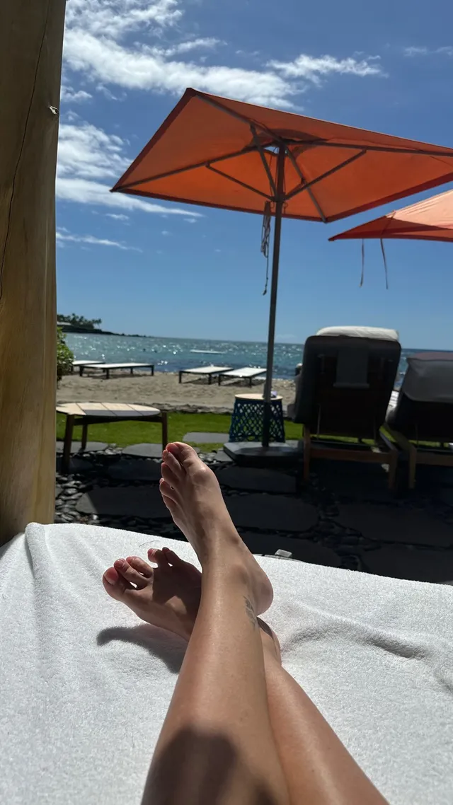 Sarah Michelle Gellar resting crossed bare legs on a beach lounger.