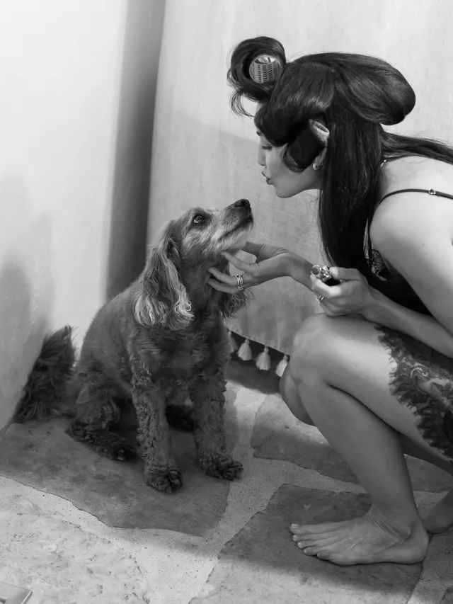 Danielle Campbell crouching beside a dog for a black-and-white photograph.