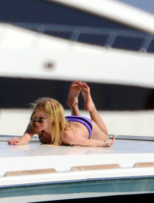 Avril Lavigne lying on a boat with her bare soles raised.