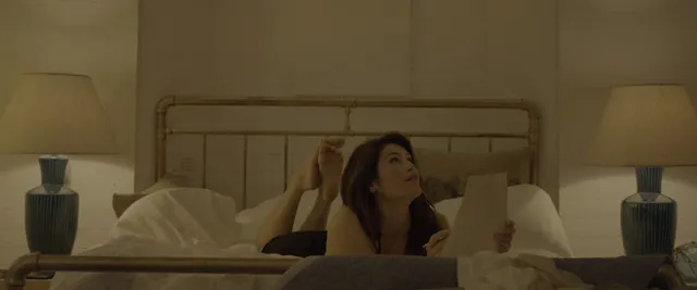 Gemma Arterton sitting up in bed in a softly lit scene.