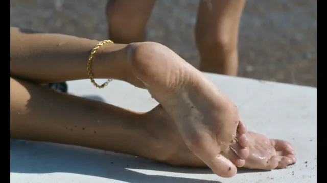 Dakota Johnson resting bare feet on an outdoor ledge.