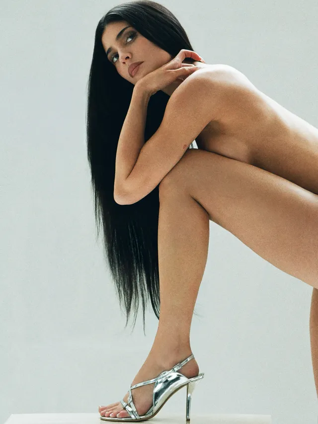 Kylie Jenner posing in metallic heels for a studio photograph.