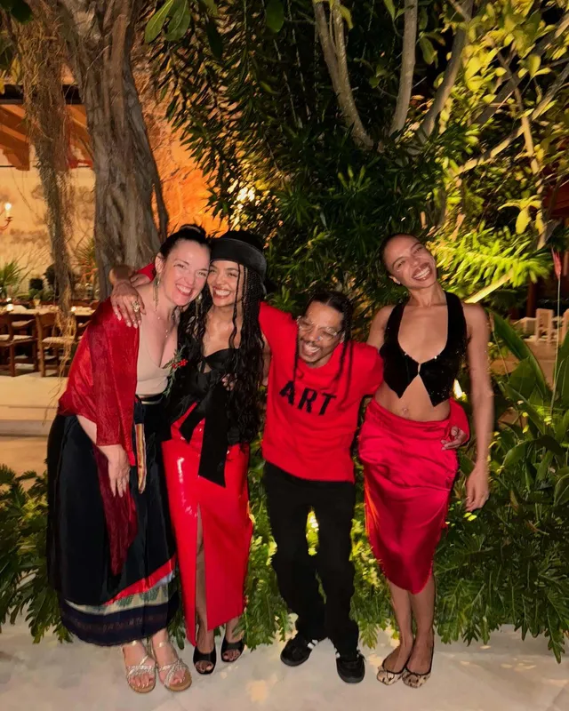 Tessa Thompson posing with a group in evening outfits.
