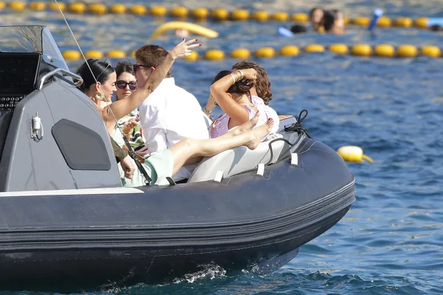 Katy Perry sitting aboard a boat with bare feet raised.