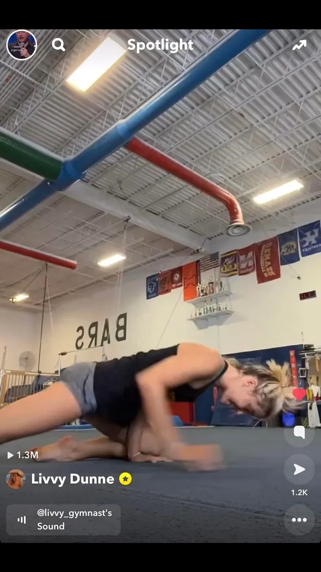 Olivia Dunne training on a mat inside a gymnastics hall.