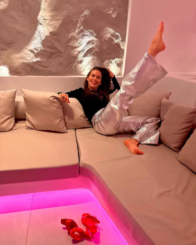 Hayley Atwell reclining on a sofa with one leg raised.