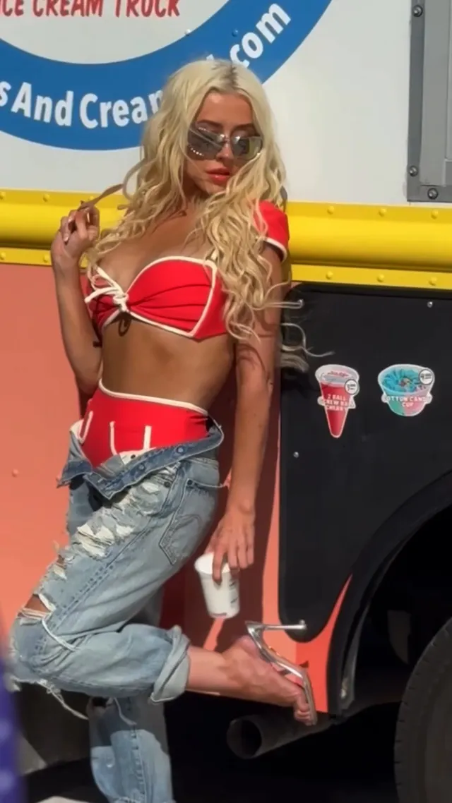 Christina Aguilera posing beside an ice-cream van in jeans and heels.