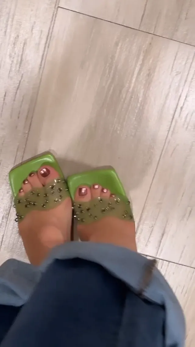 Isabela Merced wearing green embellished heels beneath blue jeans.
