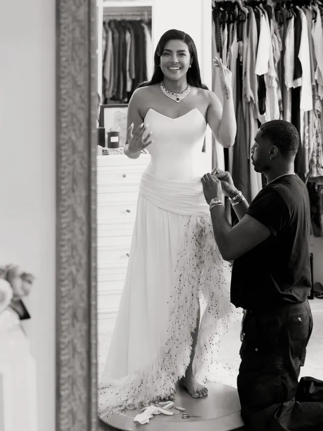 Priyanka Chopra Jonas wearing heeled sandals and a long white dress during a fitting.