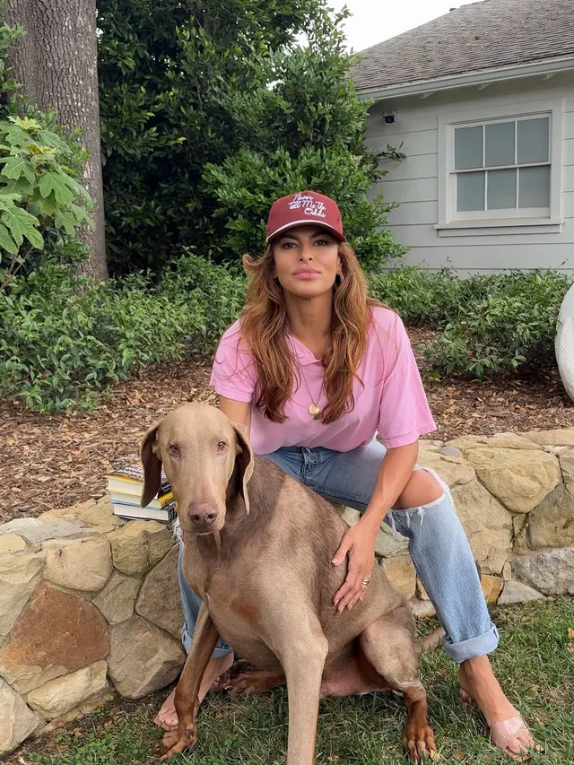 Eva Mendes sitting outdoors beside a large dog.