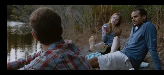 Willa Fitzgerald sitting barefoot beside water in a scene.