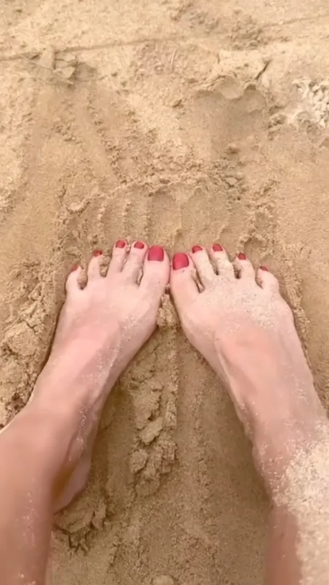 Jessica Alba showing bare feet on beach sand.