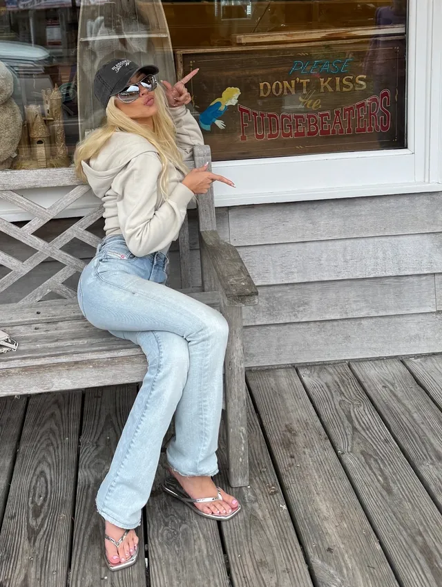 Christina Aguilera sitting outdoors in jeans and metallic heels.