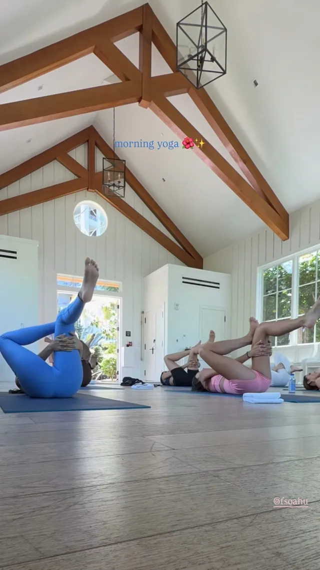 Victoria Justice stretching on a mat beneath wooden ceiling beams.