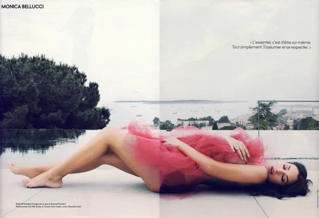 Monica Bellucci lying outdoors in a red outfit.