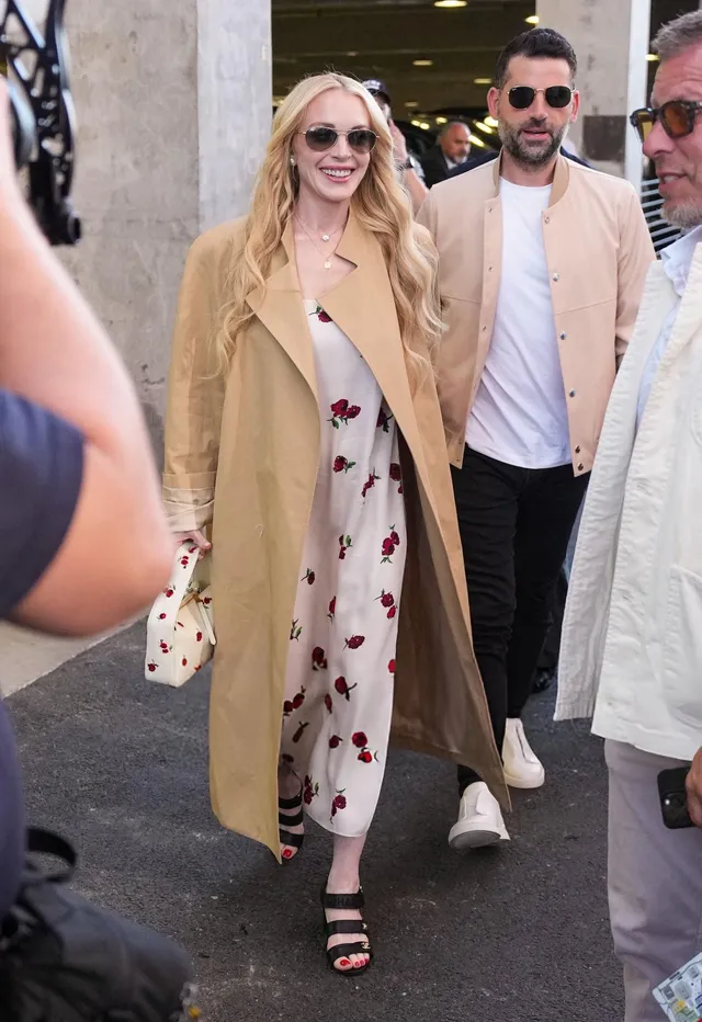 Lindsay Lohan walking outdoors in a long coat with a companion.