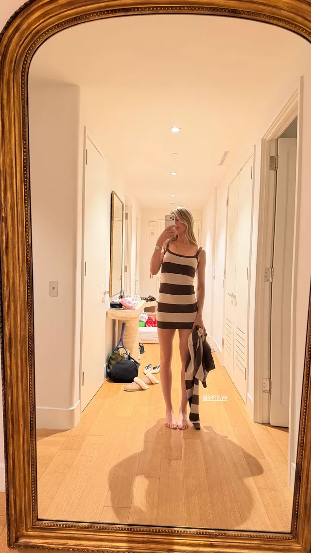 Eugenie Bouchard taking a mirror photograph in flat sandals and a striped dress.