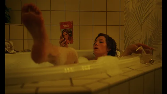 Jessica Biel a screen scene relaxing in a bathtub with feet raised.