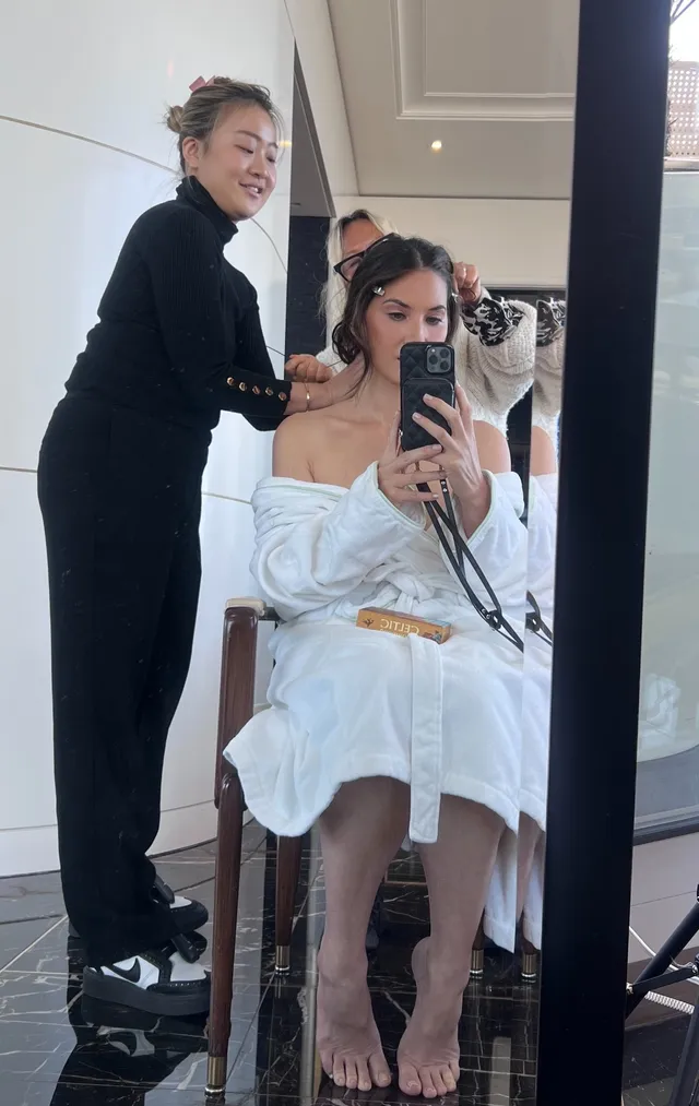 Olivia Munn sitting barefoot while having her hair styled.