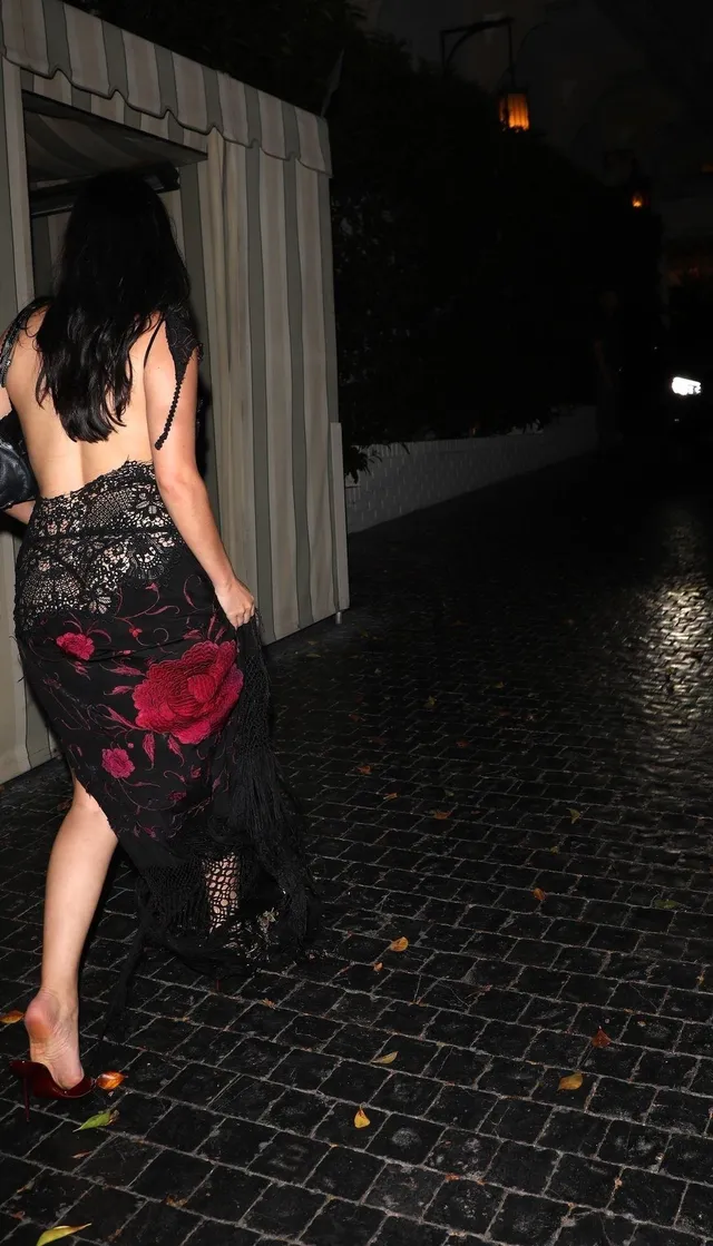 Dafne Keen walking on a sidewalk in a patterned dress and heels.