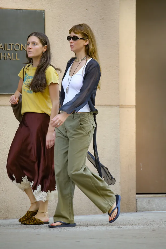 Jennifer Lawrence walking outside with a friend in sandals.