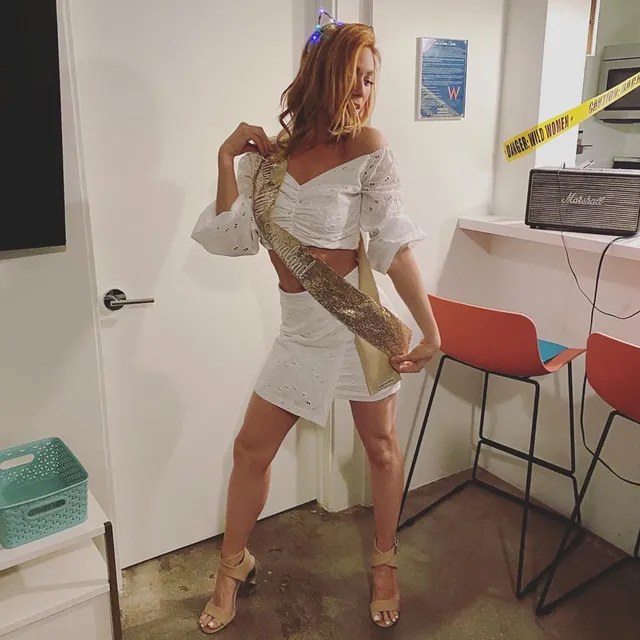 Brittany Snow posing backstage in a short white dress.