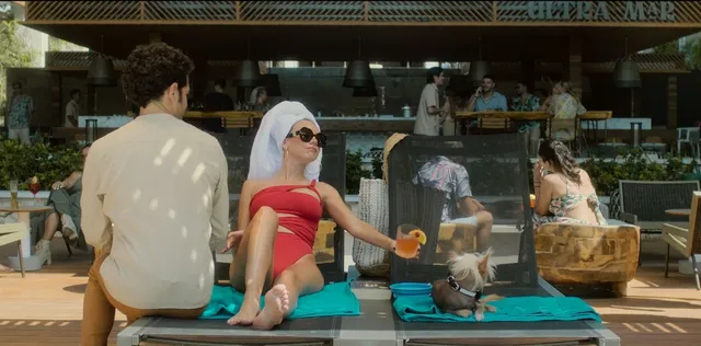 Ester Expósito reclining barefoot on an outdoor lounger during a screen scene.