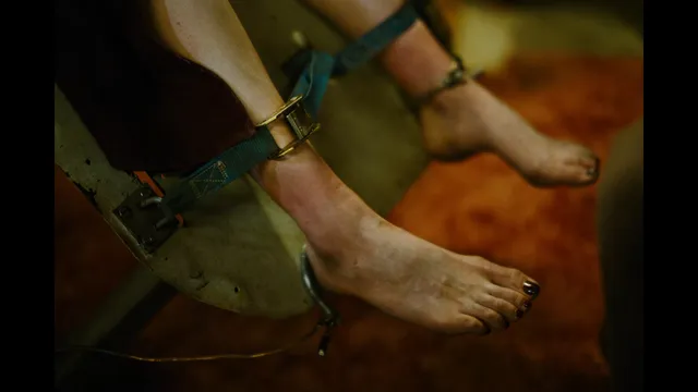 Emma Stone holding her bare feet above a patterned surface.