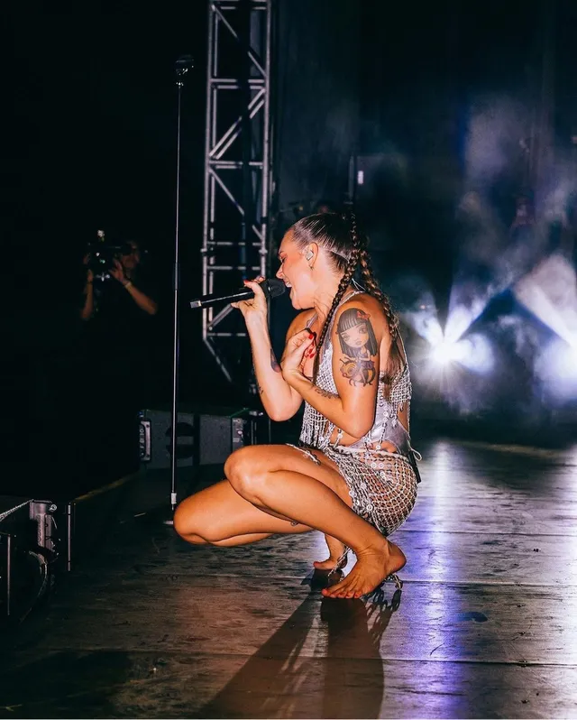 Tove Lo crouching barefoot on stage while singing.