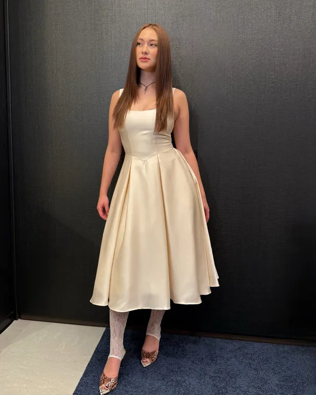 Lola Tung wearing a cream dress and pointed patterned heels.