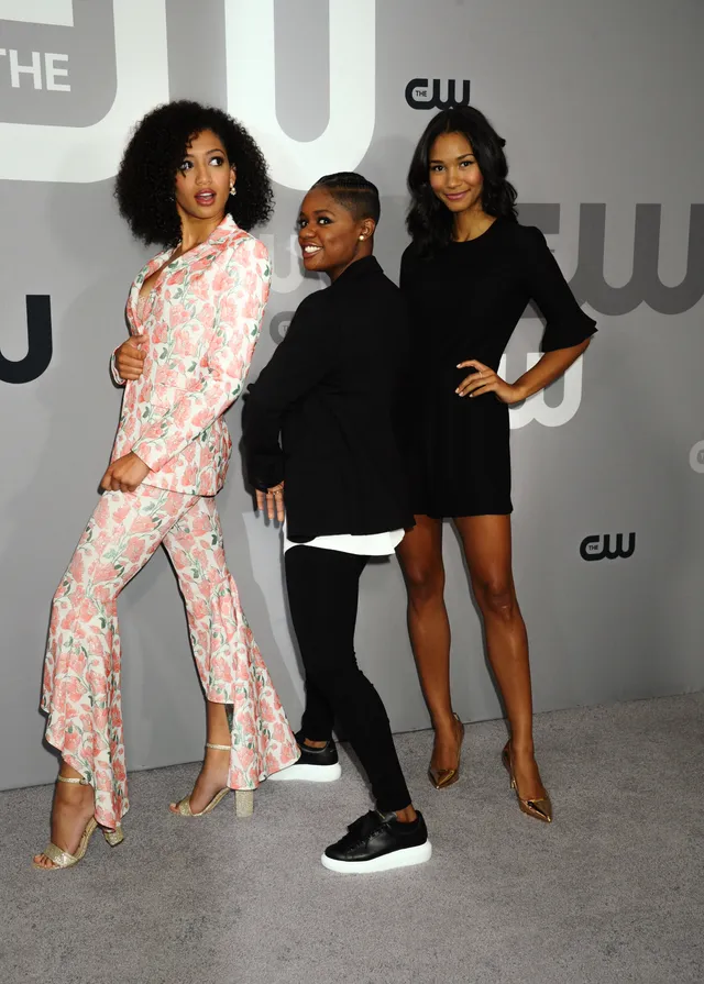 Samantha Logan posing with friends in a floral suit and gold heels.