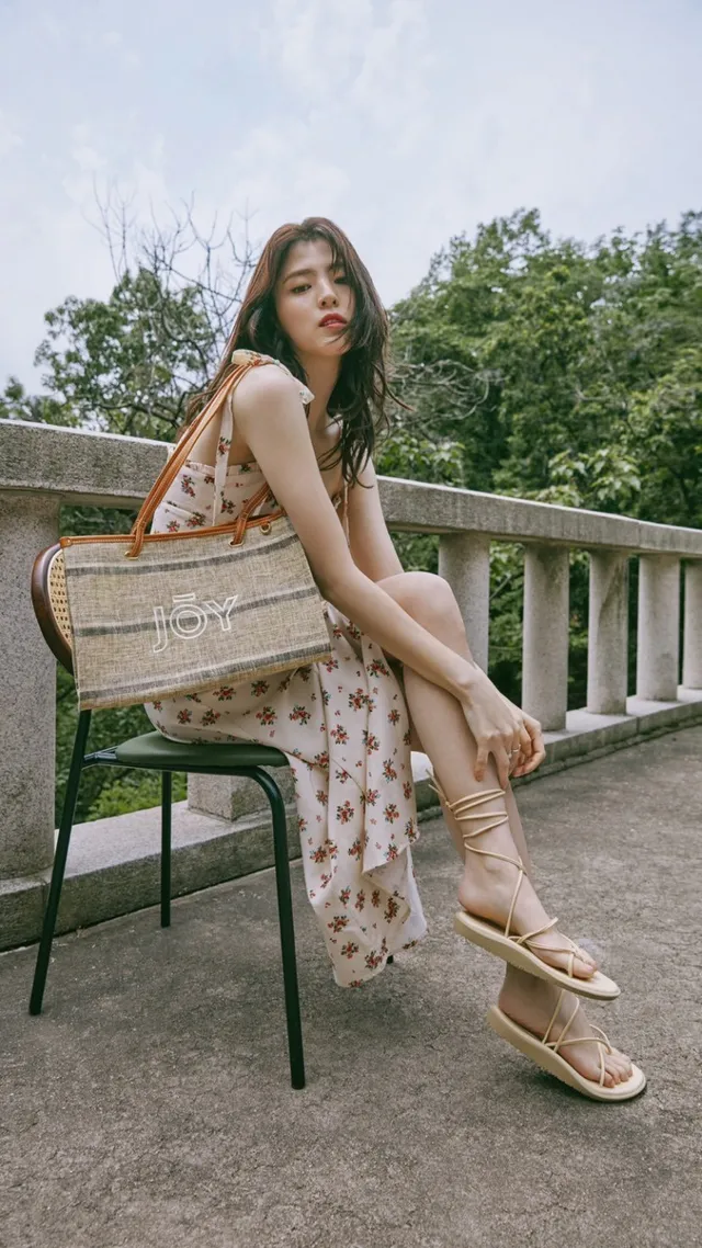 Han So-hee sitting outdoors in a floral dress and sandals.