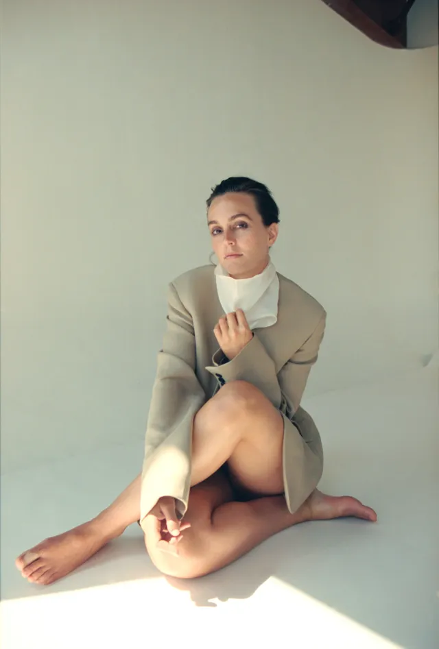 Leighton Meester sitting on the floor in a tailored cream outfit.
