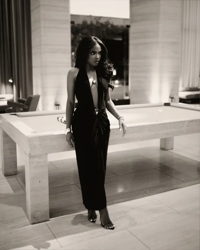 Ryan Destiny posing in a black dress and open-toe heels for a monochrome portrait.