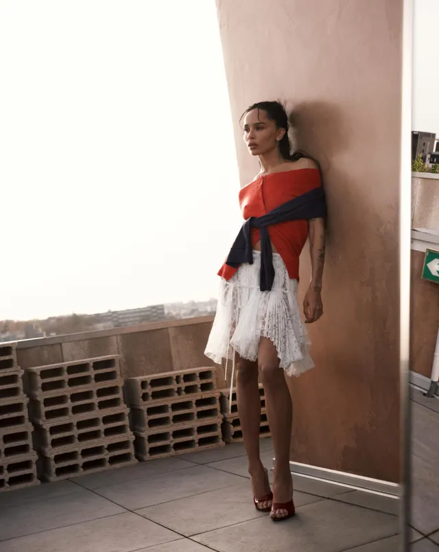Zoë Kravitz standing beside a wall in a patterned short dress.