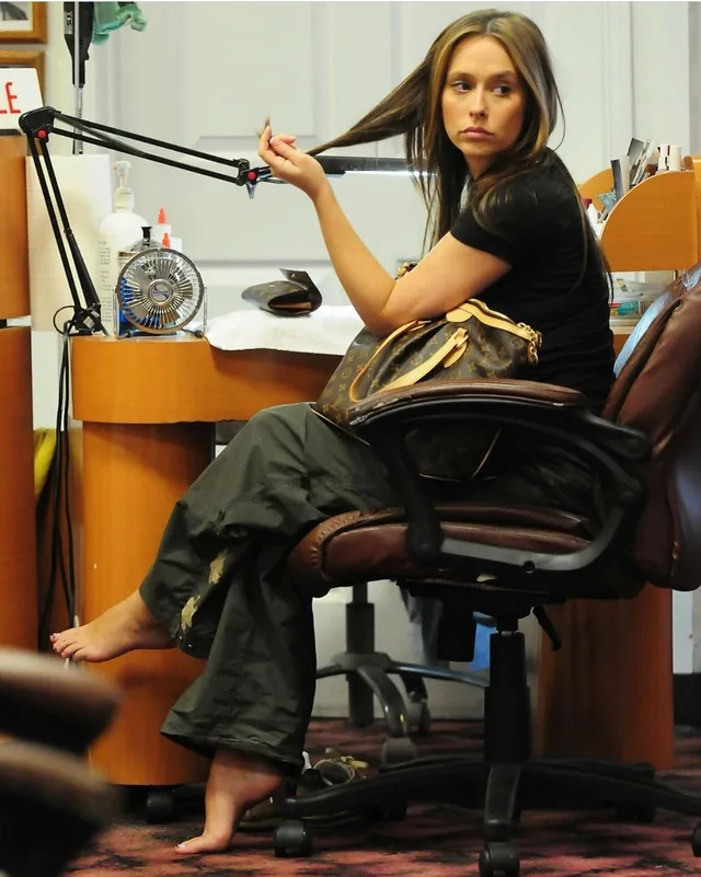 Jennifer Love Hewitt sitting barefoot at a desk in a recording studio.