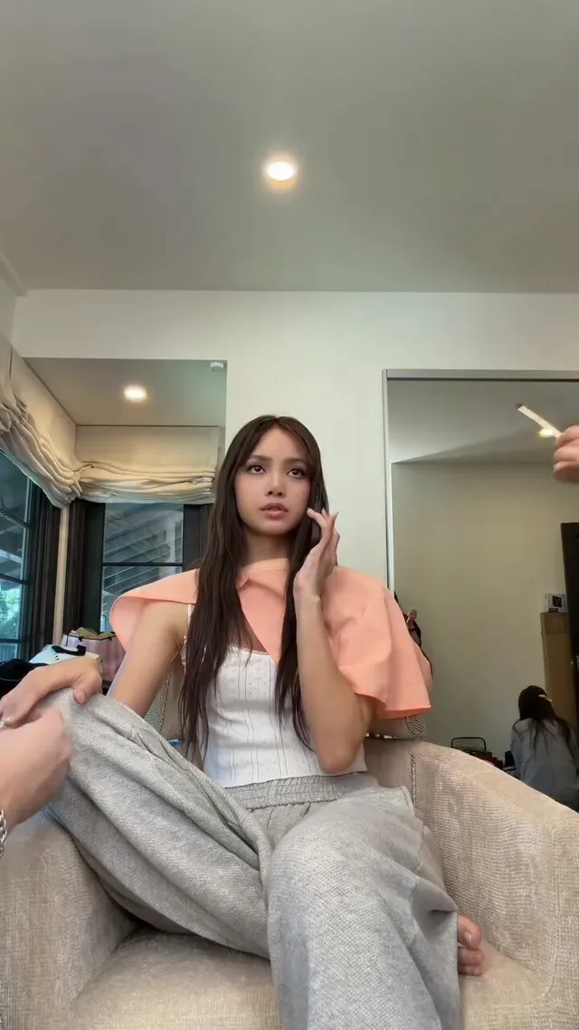 Lisa (Lalisa Manobal) sitting in a chair wearing grey casual clothing.
