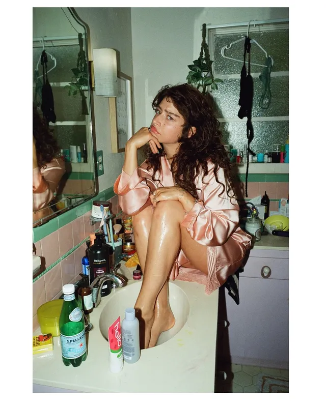 Odessa A'zion crouching barefoot on a bathroom sink.