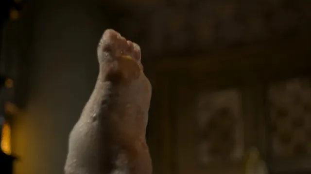 Gemma Arterton raising a bare foot in a dimly lit scene.