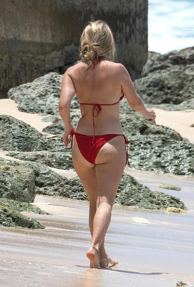 Alice Eve walking through shallow water.