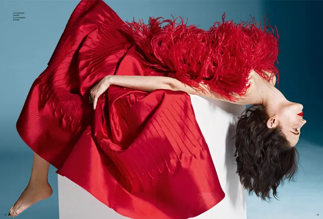 Eva Green reclining against a teal backdrop in a flowing red gown.