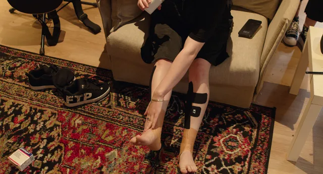 Billie Eilish a close view of a taped ankle and bare foot.