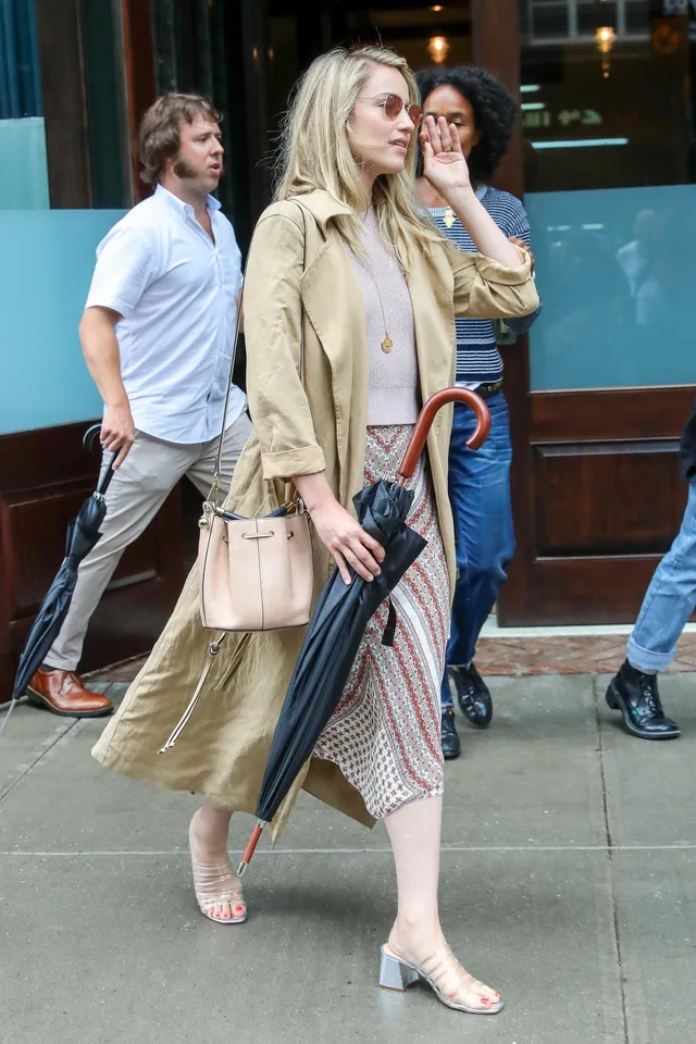 Dianna Agron walking on a pavement in a coat and flat shoes.