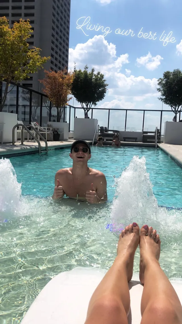 Brec Bassinger reclining barefoot beside a swimming pool with a companion.
