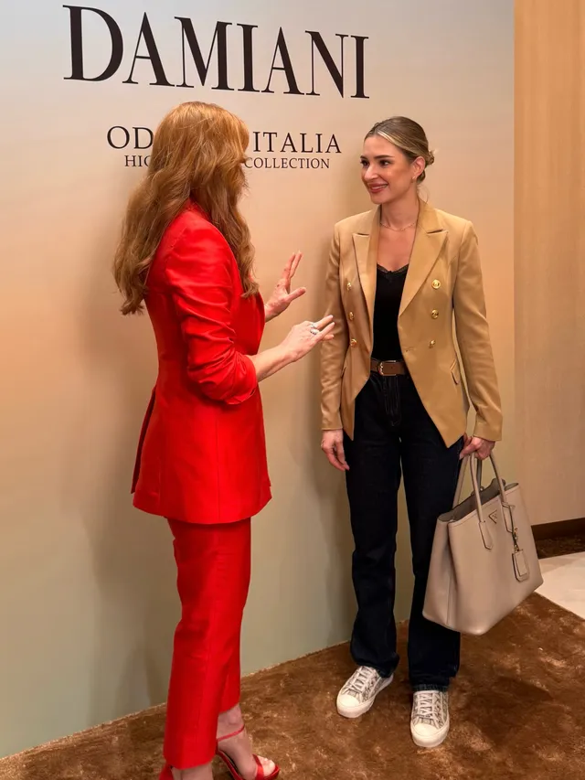 Jessica Chastain talking with another guest in a red trouser suit.