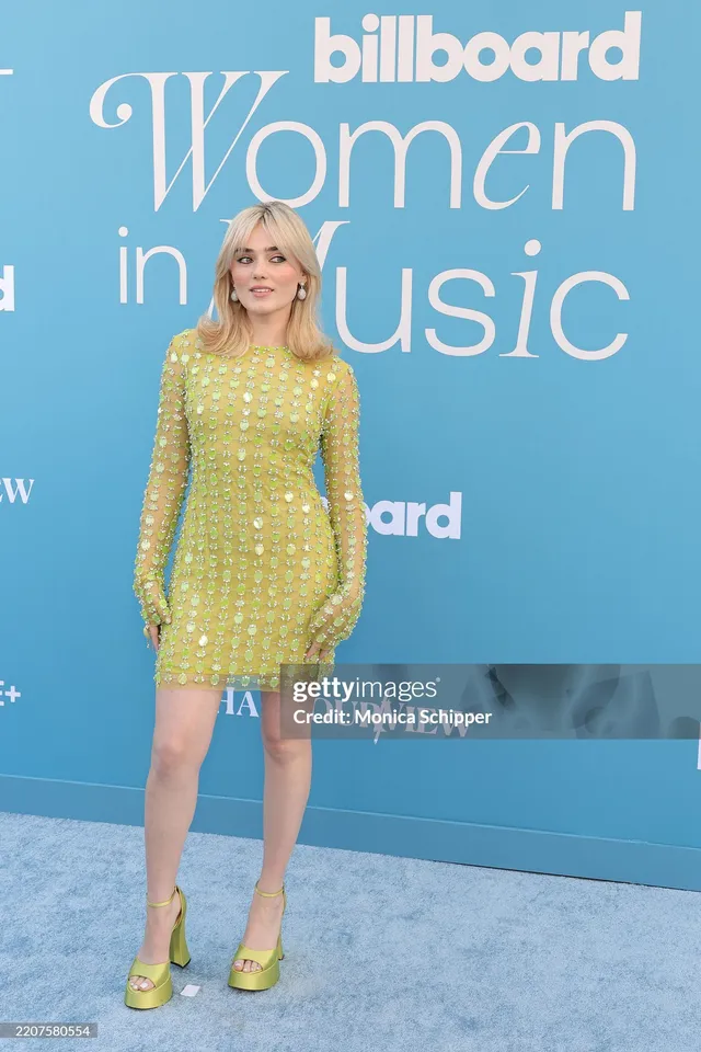 Meg Donnelly posing in a green embellished dress and matching platform heels.